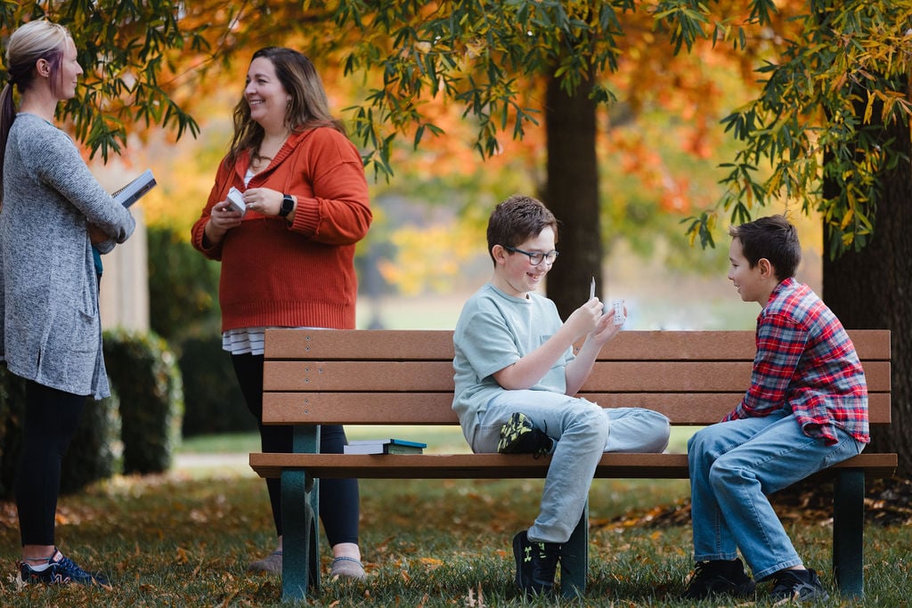 Homeschool parents discuss the curriculum while two boys practice their mathematical grammar.